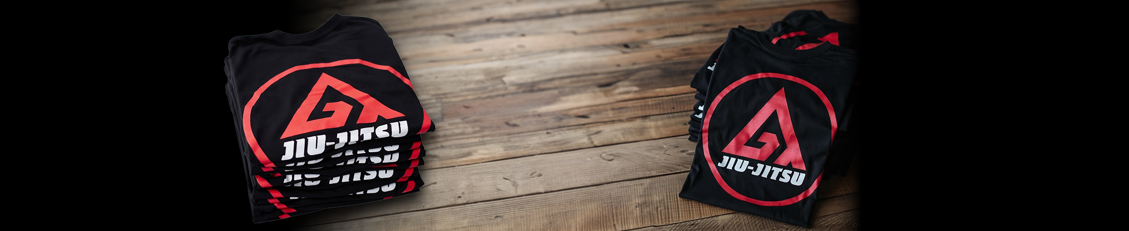 Black T-shirt with red and white 'BJJ' logo on a wooden surface